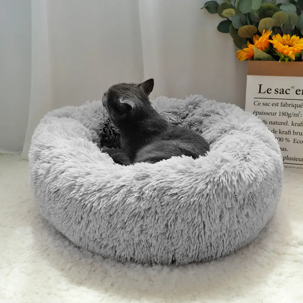 black cat laying snuggled in the warm fleece pet bed the light grey color